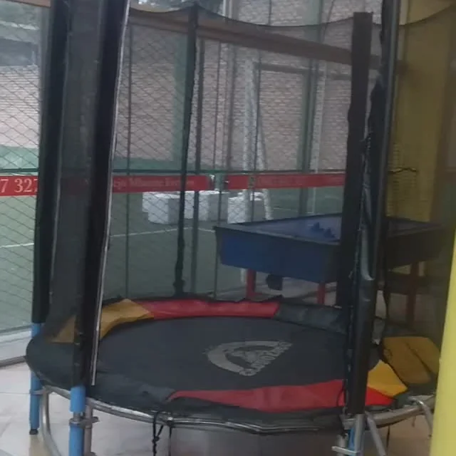 Cama elástica con red y la cancha sintética de fondo