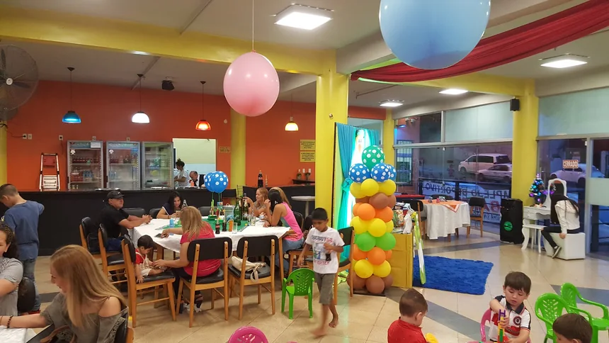 Cumpleaños en el salón con globos, mesas y chicos jugando